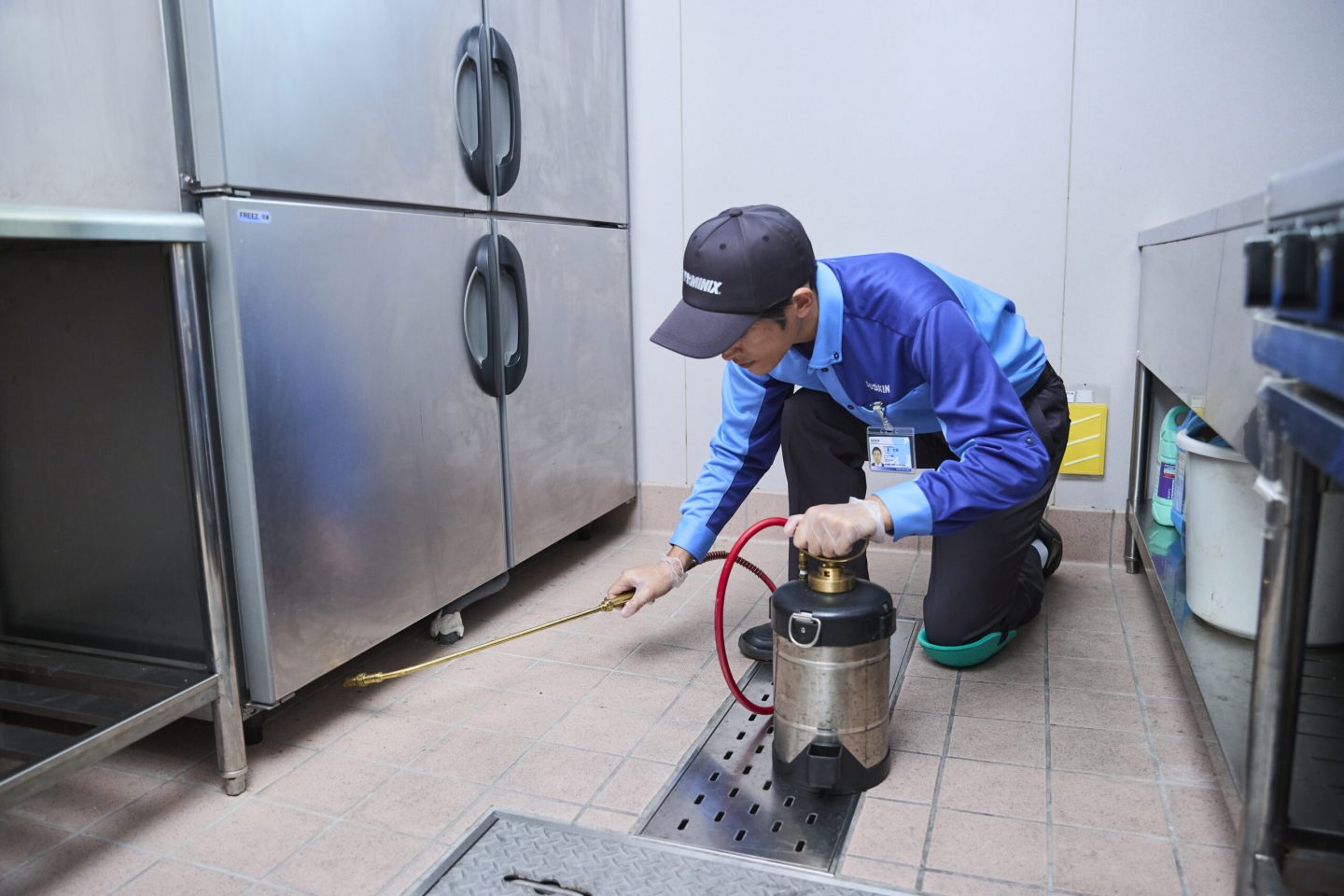 チョウバエ駆除サービス_厨房冷蔵庫下_男性_薬剤散布18413